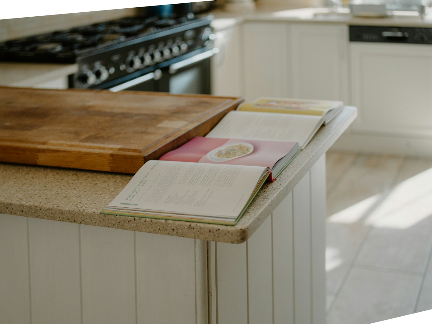 Open cookbooks spread across a sunlit kitchen counter.
