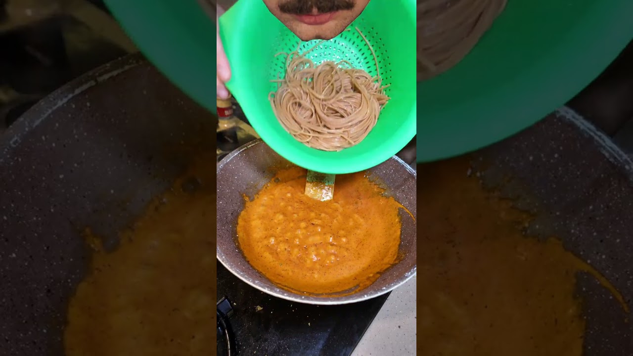 A vertical cooking video showing pasta being added to a pan of sauce.